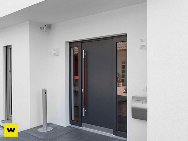 Moderne Haustür aus Aluminium mit Glaseinsätzen und Edelstahlgriff an weißer Fassade.